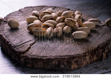 Pistachios On Wooden Table In The Foreground With Darkened Background