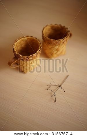 Two Wicker Mugs And A Dry Flower On The Table