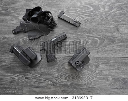 Gun Black, Spare Magazines And Leather Holster On Grey Background.