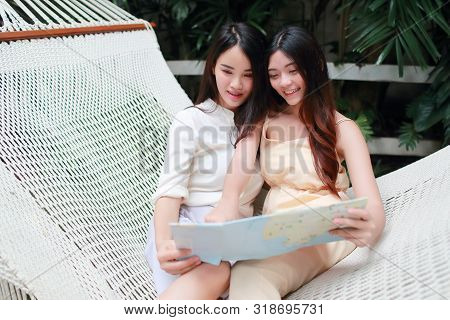 Young And Cute Asian Women Lying In A Hammock And Searching Location In A Map During Holiday
