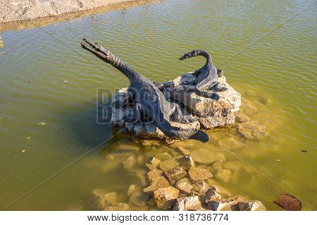Dinosaurs Statues On The Pond In Geosfera Park In Jaworzno, Poland