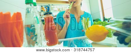 Portrait Of Female Standing Near Open Fridge Full Of Healthy Food, Vegetables And Fruits. Portrait O