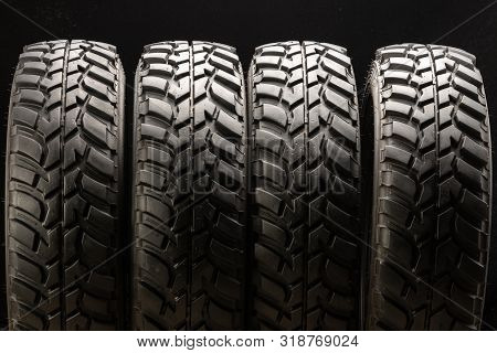 Four Off-road Tires On Black Background. Close Up.