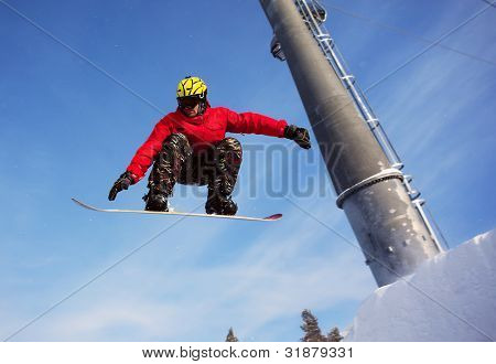 Snowboardista skoky vzduchem s tmavě modrou oblohou v pozadí