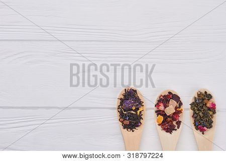 Set Of Dry Tea Leaves In Spoons For Tea Ceremony. Spoons With Variety Of Dry Tea Leaves On Wooden Ba