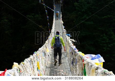 Trekker Crossing Metal Suspension Bridge In Nepal, Himalayas