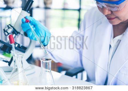 Women Scientist Looking Through Microscope In Laboratory. Women Scientist Doing Some Research With D