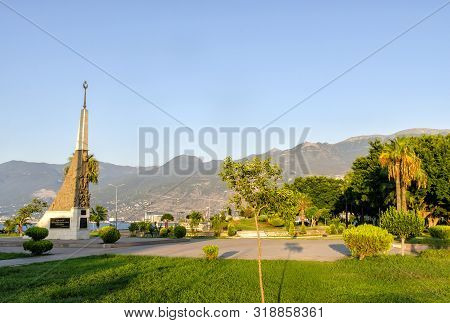 Turkey, Hatay - August 24, 2019: The Monument At Iskenderun With Trees And Mouontain