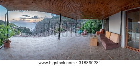 Sunset In The Distance Over The Ocean With Mountains And Dinner Tables And Trees