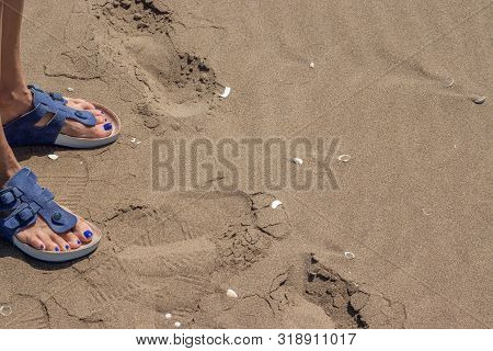Woman Feet With Sandals On The Sand