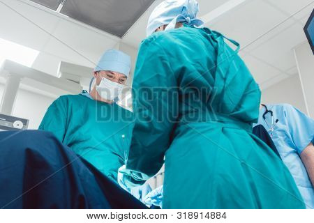 Medical doctors performing operation in hospital using scalpel and tools