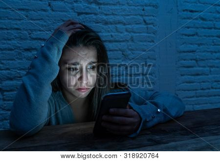 Young Sad Woman Alone Looking At Smart Phone In Fear Suffering Internet Harassment And Cyberbullying