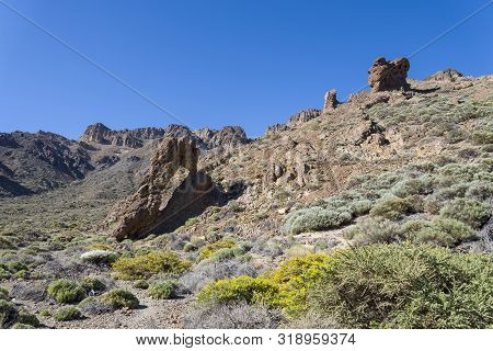 Mountains And Shrubs Near The Volcano Teide, Partially Covered With Clouds. Bright Blue Sky. Teide N