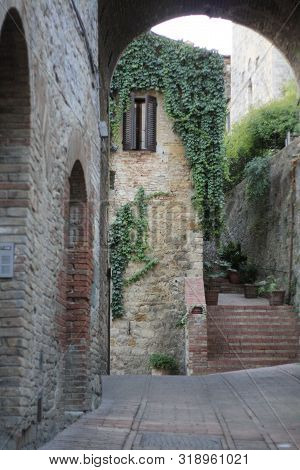 Ancient Tuscan Walled City Houses With Towers And Stone Walls And Paved Cobbled Streets In Italy