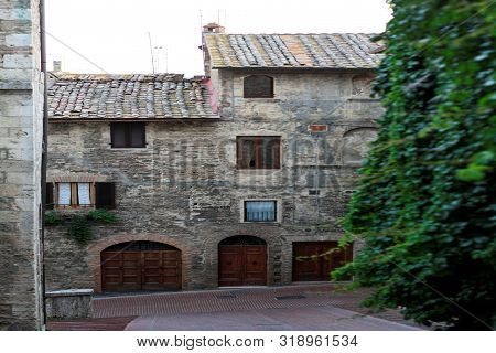Ancient Tuscan Walled City Houses With Towers And Stone Walls And Paved Cobbled Streets In Italy