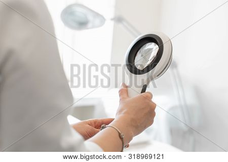 Doctor Trichologist Dermatologist Holding A Dermatoscope In Clinic.