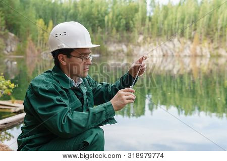 Industrial Ecologist Or Chemist Takes A Sample Of Water From Lake At The Site Of A Flooded Mining Pi