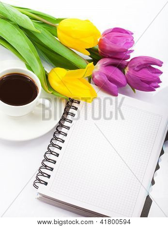 Flowers, coffee and notebook. Closeup.