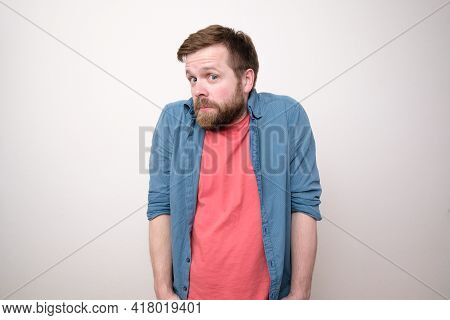 Bewilderment Bearded Man In Casual Clothes Looks Thoughtfully And In Surprise, Thrusting Hands Into 