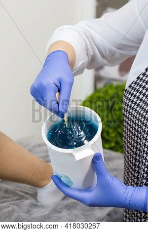 Closeup Of Female Beautician Hands Mixing Liquid Colorful Wax In Plastic Container For  Sugaring Pro