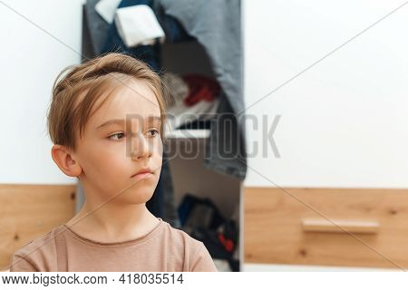 Boy Standing Near Messy Clothes On Shelf. Preteen Boy With Dirty Clothing In His Room. Messy Home Ki