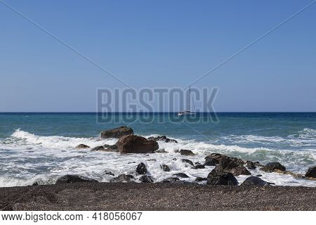 Coast And Beach Of Vlychada On Santorini Island In Greece. In The Background Blue Sky And Waves At S