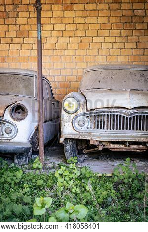 Two Vintage Cars Left Standing And Falling Apart In A Shelter - Image