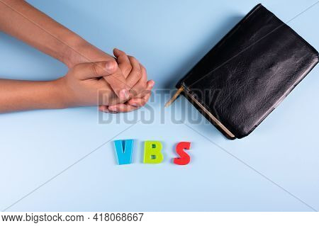 Female Hands Is Praying Next To Black Bible And Abbreviation 