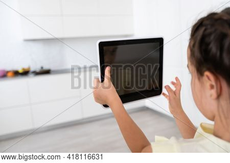 Shot Of Little Girl Using A Domotic System With Her Digital Tablet While Standing At Home.