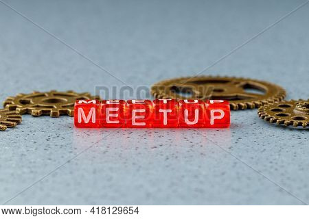 Meetup Inscription From Letters On Cubes On A Light Blue Background On The Back Of Metal Gears