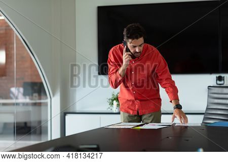 Portrait of caucasian businessman standing in meeting room talking on smartphone. independent creative design business.