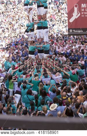 Tarragona, Spain, September 19, 2019 - Helmeted Little Girl Climbing To Top Of Human Castells Tower.
