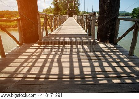 Dark Shadow In The Daytime On A Wooden Suspension Bridge That Crosses A Reservoir In A Park In Thail