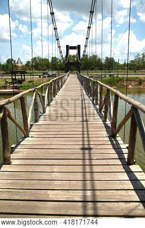 Wooden Suspension Bridge That Crosses A Reservoir In A Public Park In Thailand.