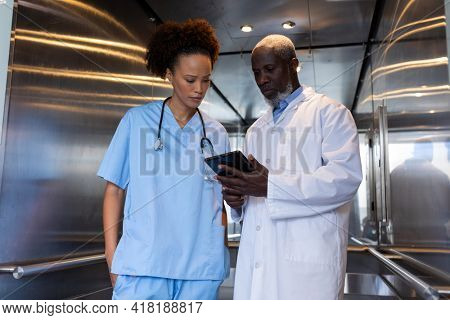 Serious diverse female and male doctors using tablet in hospital lift. medical professionals at work.