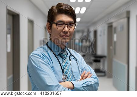 Portrait of mixed race male doctor standing in hospital corridor. medicine, health and healthcare services.