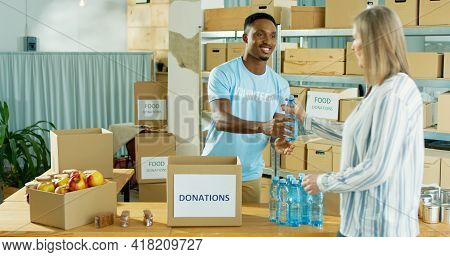 Happy African American Young Handsome Man Volunteer Smiling Working At Charity Center Giving Food To