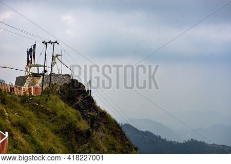 Yellow And White Iron Fencing With Flying Prayer Flags . Cloudy Sky And Mountain Ridges .