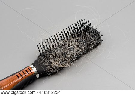 Hair Loss Problem, Hairbrush With A Lot Of Fallen Hairs On Grey Background. Bunch Of Blonde Hair On