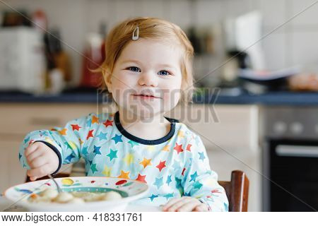 Adorable Baby Girl Eating From Spoon Vegetable Noodle Soup. Food, Child, Feeding And Development Con