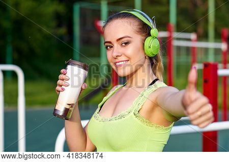 Fitness Woman With Headphones Drinking Water In Workout Sports Ground