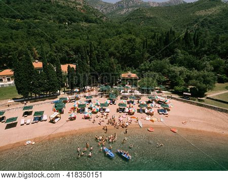Top View Of The Royal Beach In Przno. Colored Sun Umbrellas Stand On The Sand, People Swim In The Se