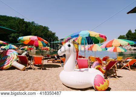 Inflatable White Unicorn On The Royal Beach In Przno Against The Backdrop Of Green Trees