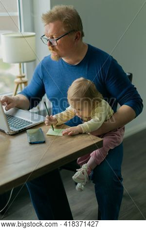 A freelance man father tries to work at home on a computer on the Internet and sits with a small child who prevents him from doing business
