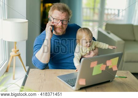 A freelance man father tries to work at home on a computer on the Internet and sits with a small child who prevents him from doing business