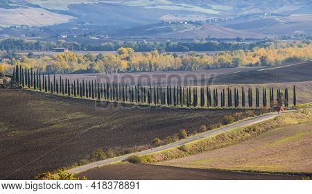 Rocca di Radicofani main tower fortification covered with morning mist. Sunrise light covering the curly clouds running over meadows and fields making light-shadows playing on Tuscany hills landscape.