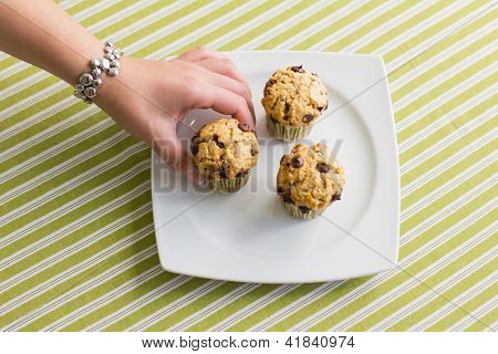 Trevlig tjej Hand ta Chocolate Chip Muffin på frukost