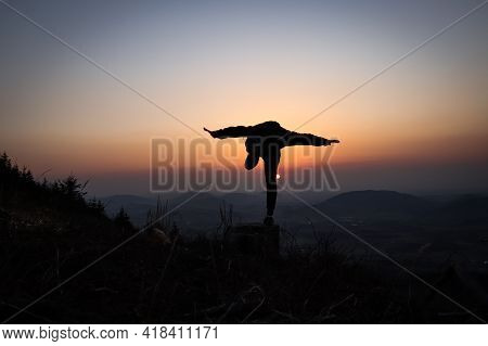 Silhouette Of A Teenager And An Athlete Testing A Dove On A Tree Stump At Sunset In The European Mou