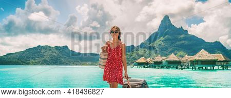 Traveling woman walking with luggage in French Polynesia on paradise Motu on Bora Bora with Mount Otemanu. Woman arriving on dream vacation destination
