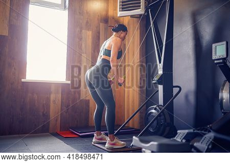 Determined Young Woman Working Out On Row Machine In Fitness Stu